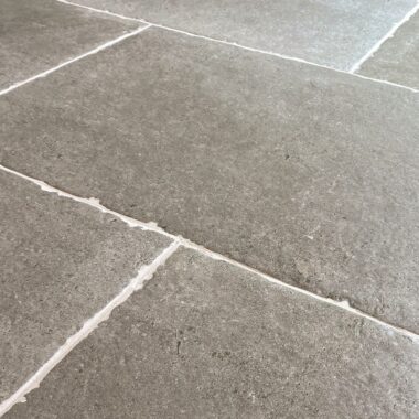 Taxos Light Grey Limestone Tiles in a patio setting. French windows in the background and patio furniture.