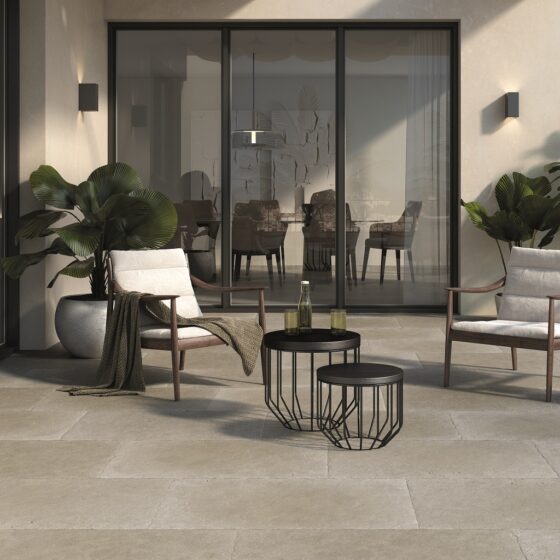 Taxos Light Grey Limestone Tiles in a patio setting. French windows in the background and patio furniture.