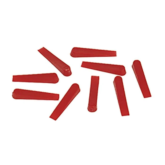 Nine red plastic cylindrical caps or plugs scattered on a plain white background.